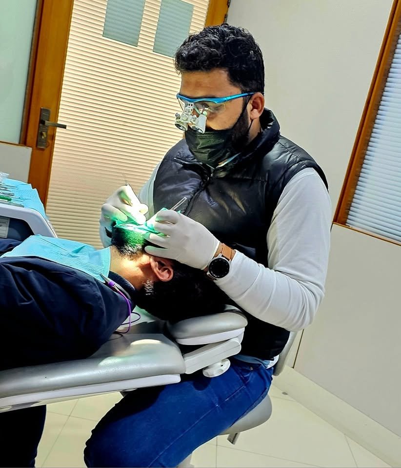 Dr. Adil Rehman Ghumman treating a patient with magnification loupes